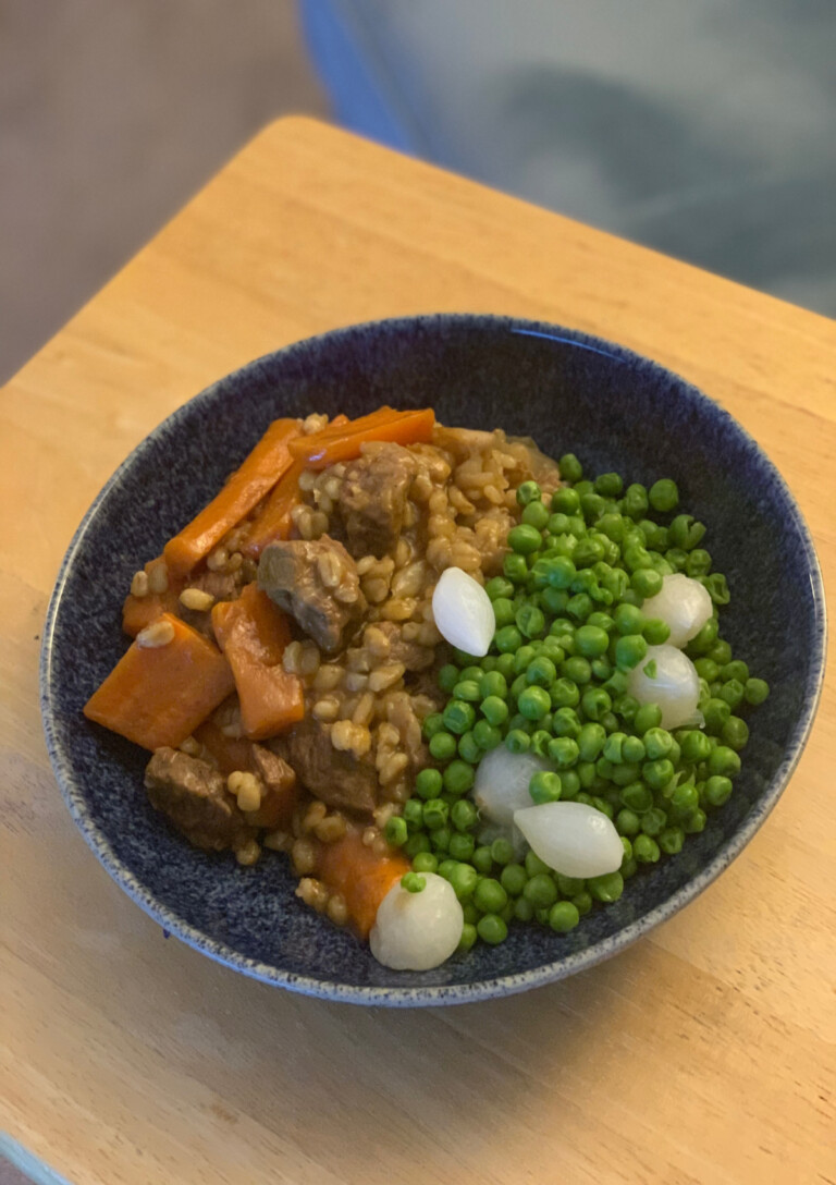 Beef and Barley Stew served in a bowl with a side of peas and pearl onions