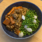 Beef and Barley Stew served in a bowl with a side of peas and pearl onions