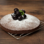 Easy Chocolate Cake recipe sprinkled with icing sugar and topped with cherries