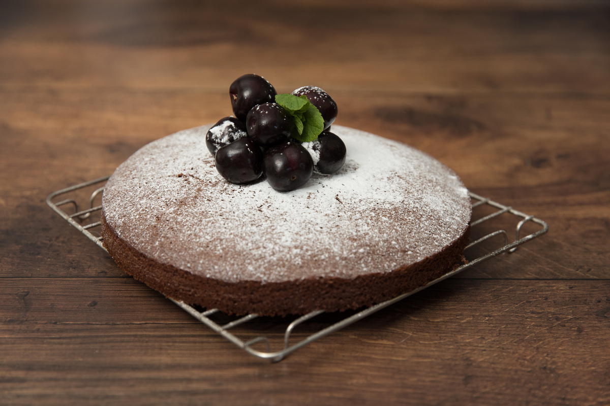 Easy Chocolate Cake recipe sprinkled with icing sugar and topped with cherries