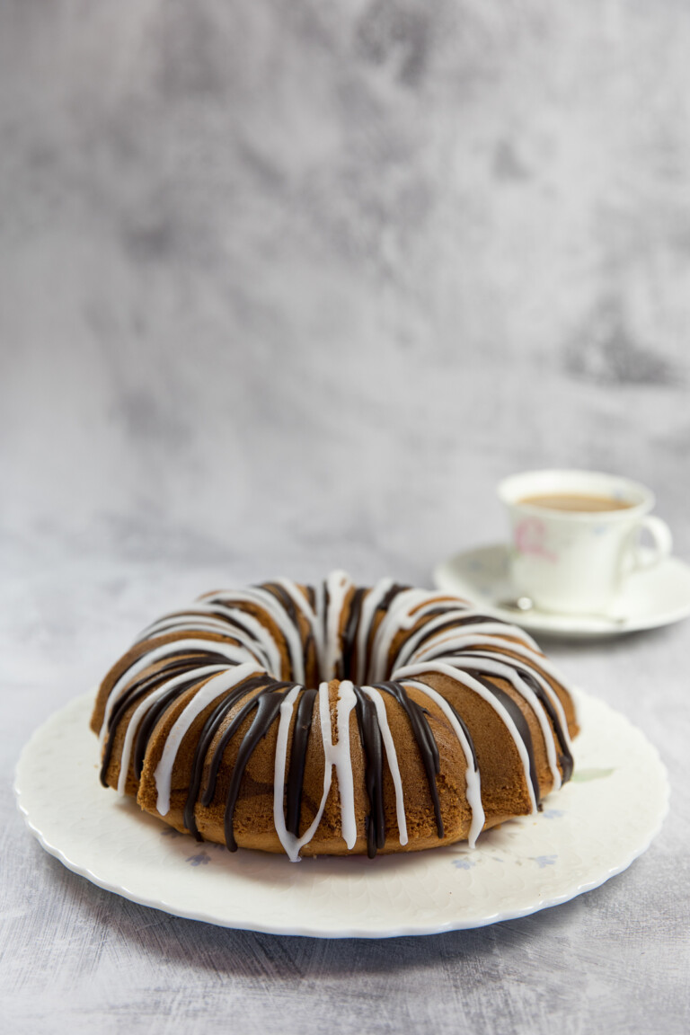 A Bundt cake with chocolate and vanilla glaze served on a cake plate