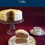 A coffee and almond cake on a glass cake stand with a slice of cake in the foreground on a china plate. There's a tea cup in the background.
