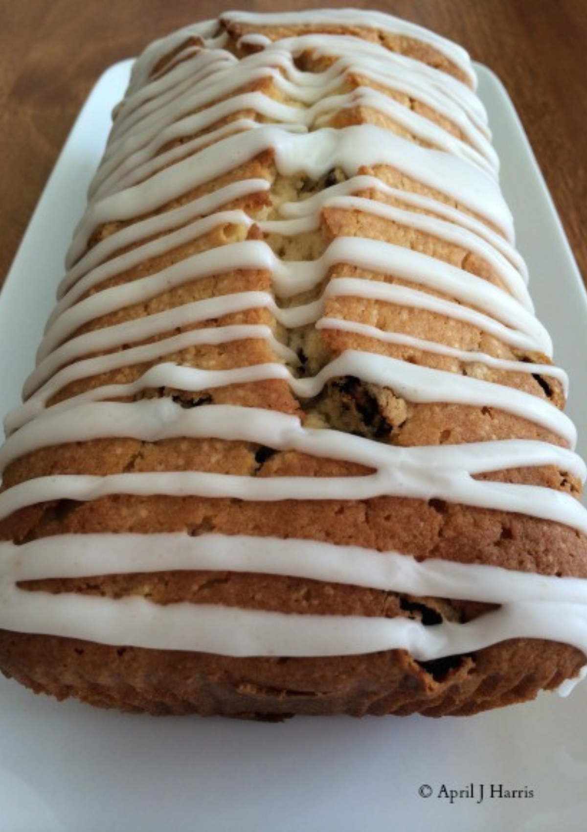 A whole glazed Lemon and Ginger Pound Cake sitting on a white plate