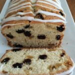 Lemon Ginger Pound Cake with Raisins Served on a white rectangular plate. There is a cut slice at the front of the cake.