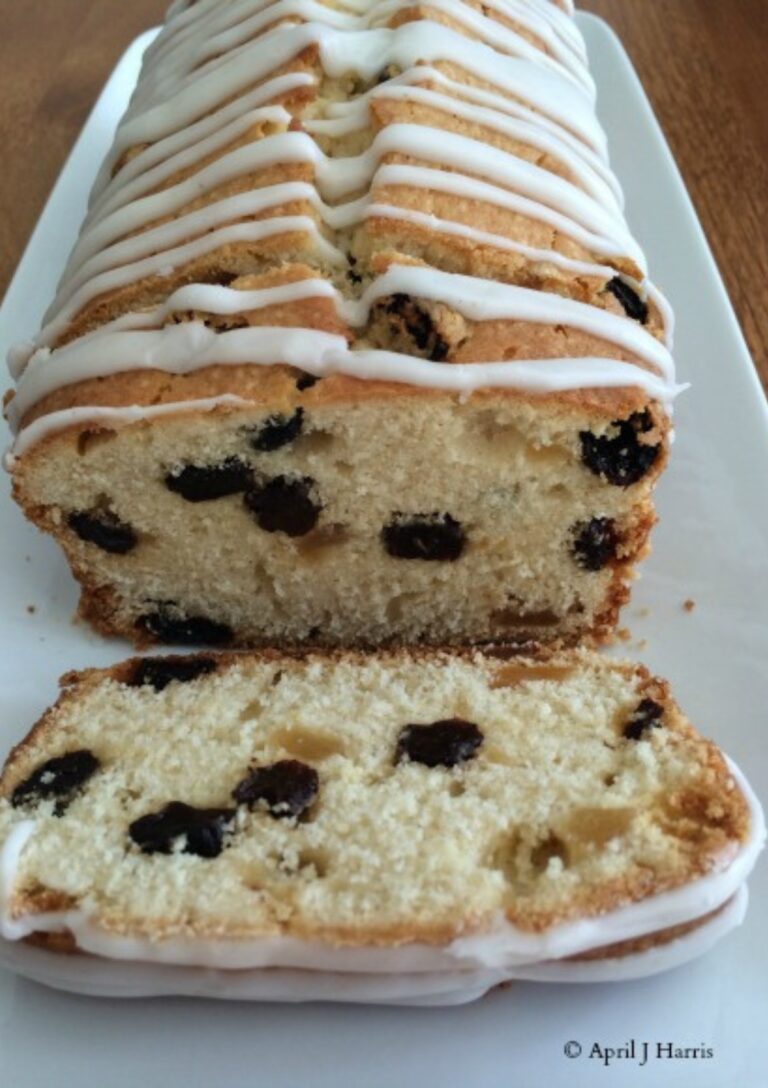 Lemon Ginger Pound Cake with Raisins Served on a white rectangular plate. There is a cut slice at the front of the cake.