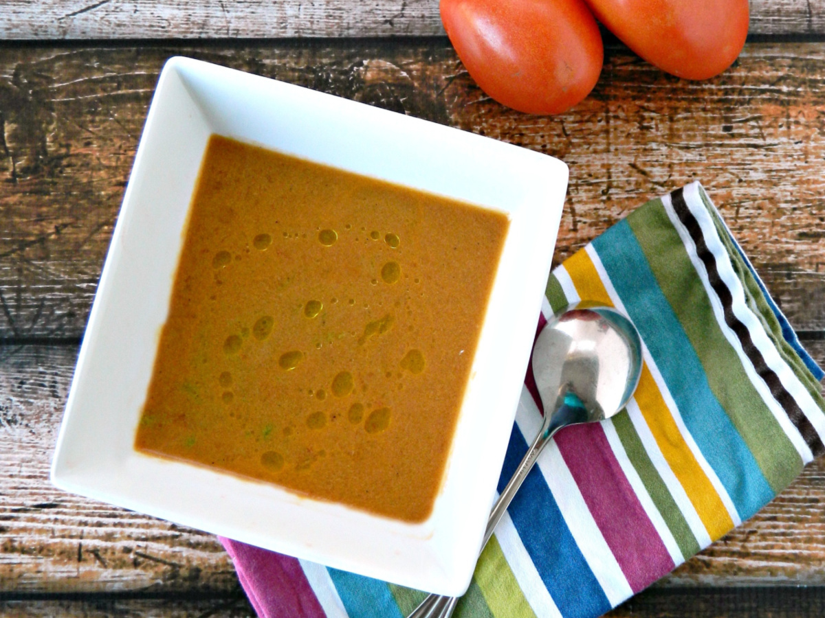 Creamy Roast Tomato Soup served in a white bowl with a napkin and spoon alongside