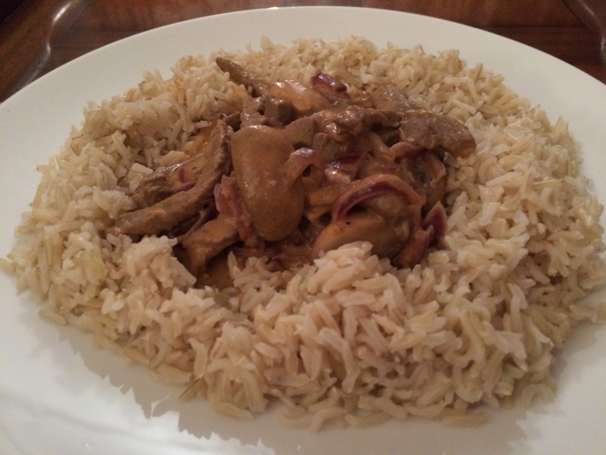 Lighter Beef Stroganoff served over brown rice on a white plate