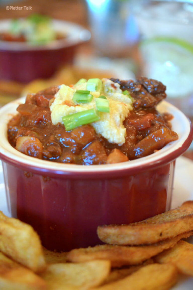 Texas Chili with Hominy served in a red bowl with sour cream on top