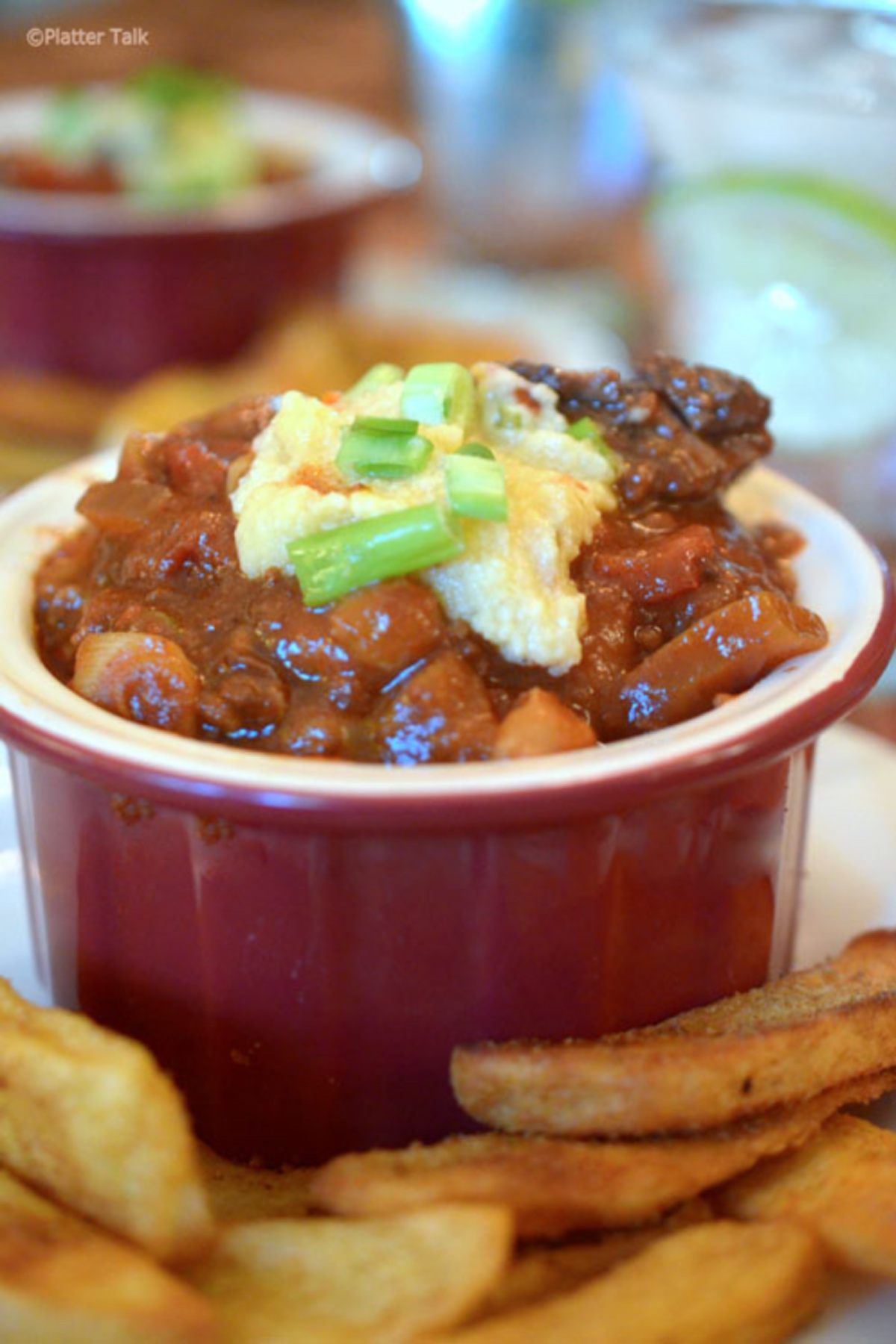 Texas Chili with Hominy served in a red bowl with sour cream on top