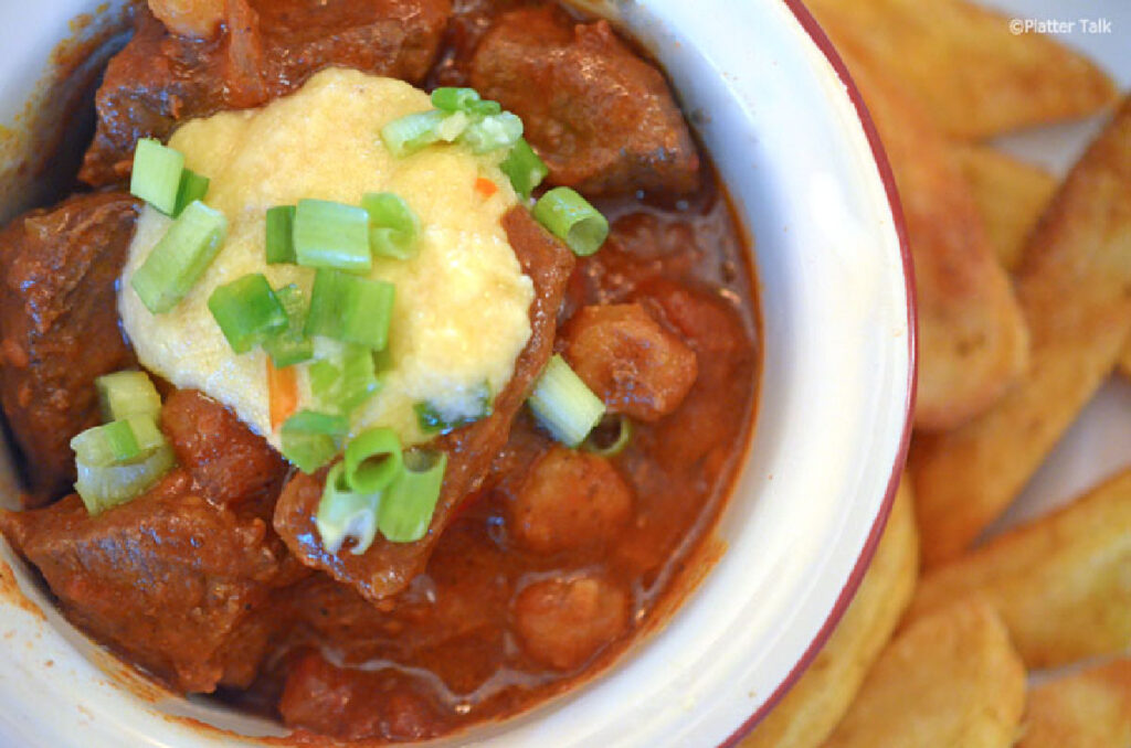 flat lay view of Texas Chili with Hominy topped with sour cream and green onions
