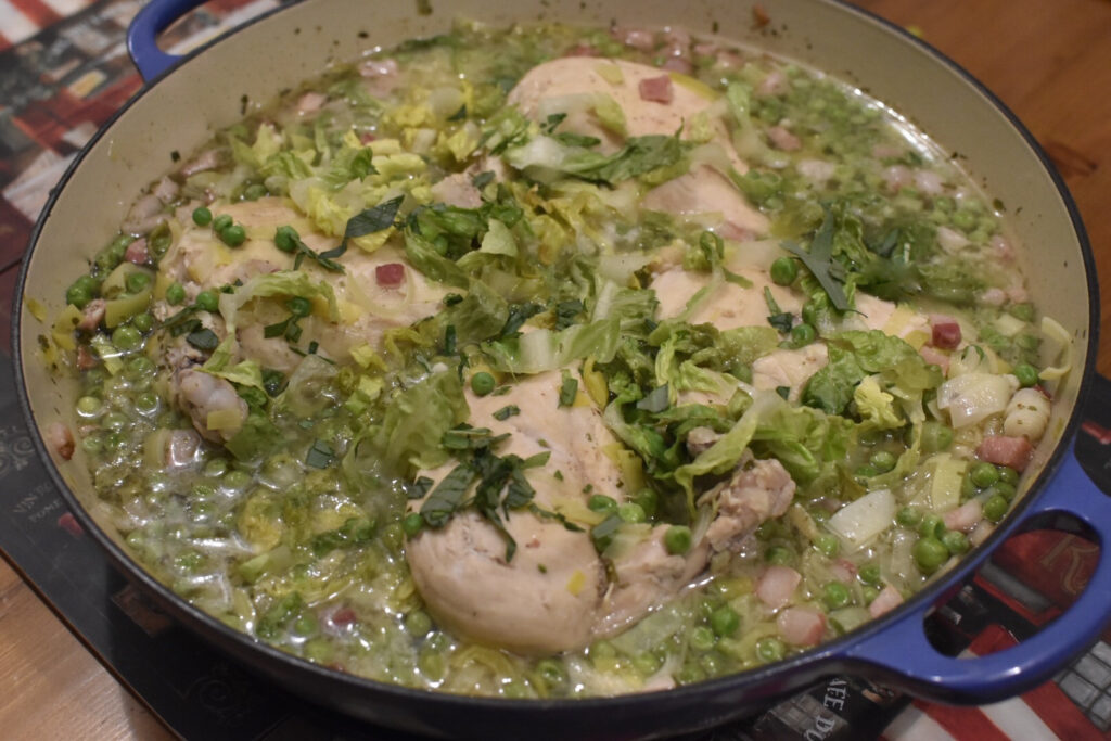 Based on a traditional French recipe, Petits Pois a la Francaise with Chicken served in a shallow blue Le Creuset casserole.