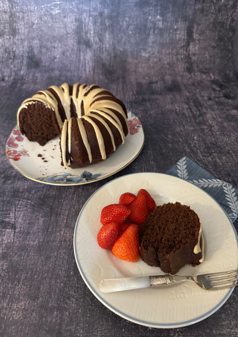 A Mocha Cake on a serving plate with a slice in the foreground.