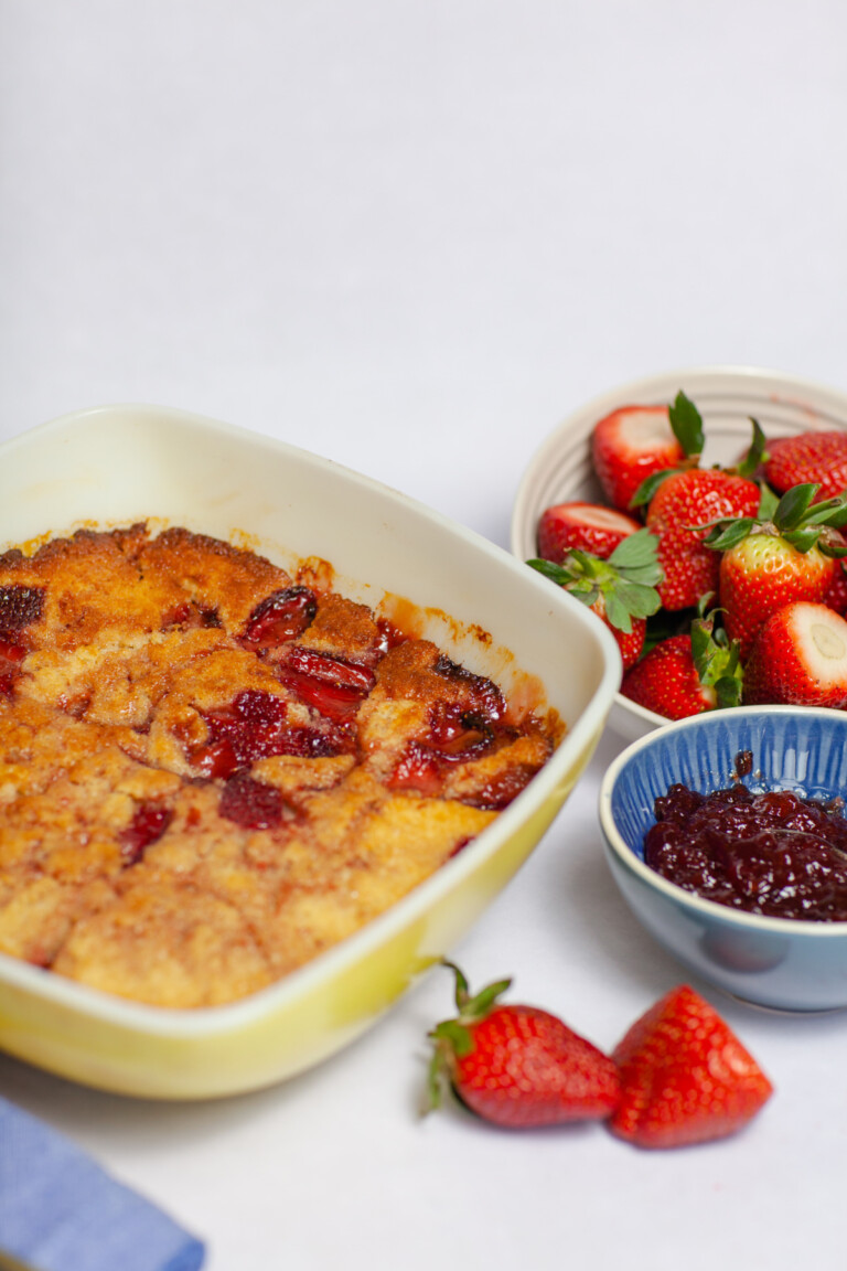 Strawberry Pudding Cake in a yellow vintage casserole with strawberries and jam alongside