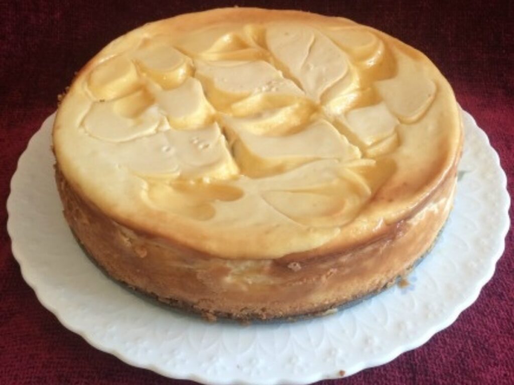 a whole Baked Lemon Cheesecake served on a white cake plate