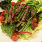 Steak and Asparagus Salad served on a white plate with a blue border