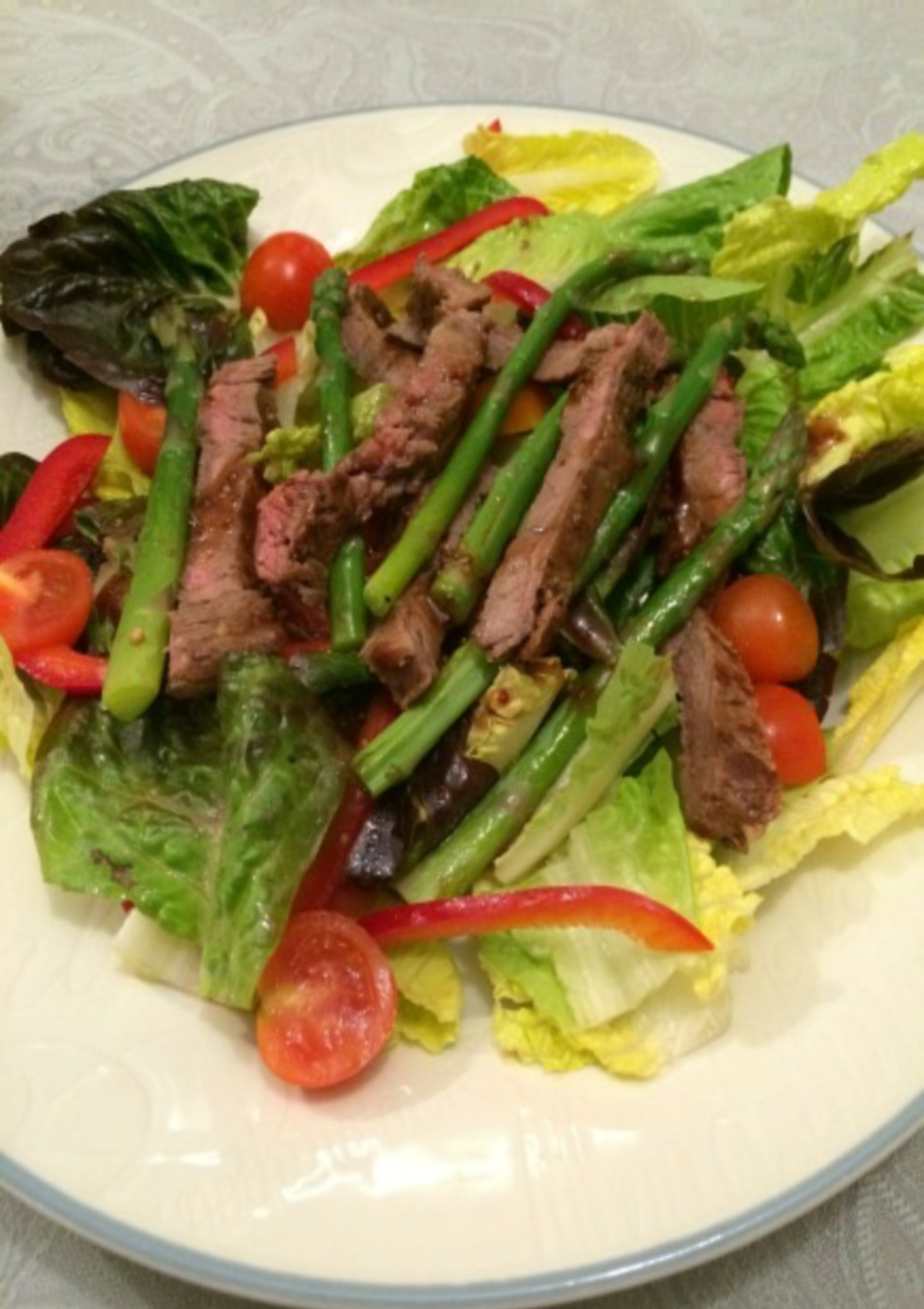 Steak and Asparagus Salad served on a white plate with a blue border