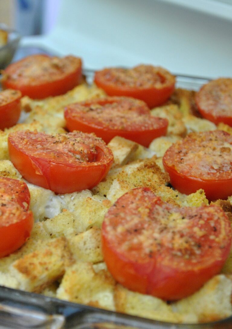 A close-up photo of Brie Basil and Tomato Strata with halved tomatoes sprinkled with Parmesan cheese on top