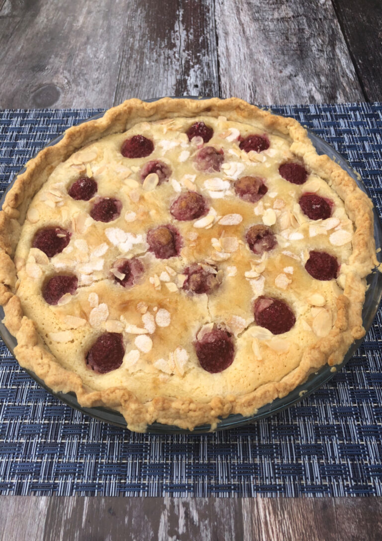 A whole Raspberry Almond Tart sitting on a blue placemat