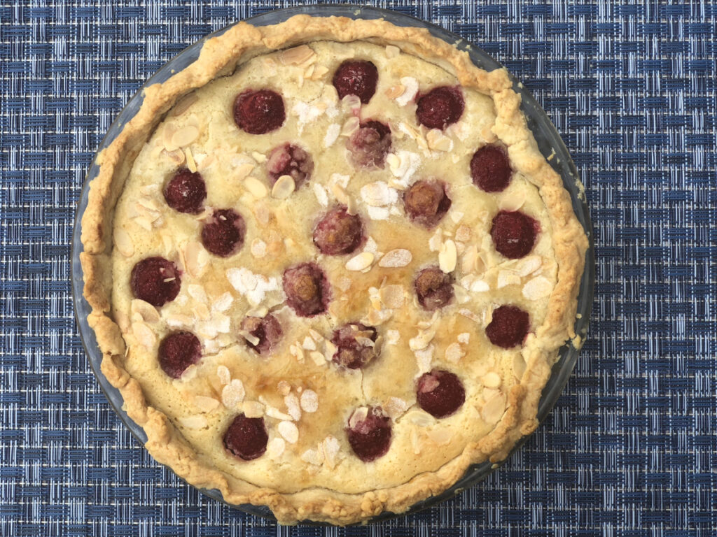 A whole Raspberry Almond Tart sitting on a blue placemat