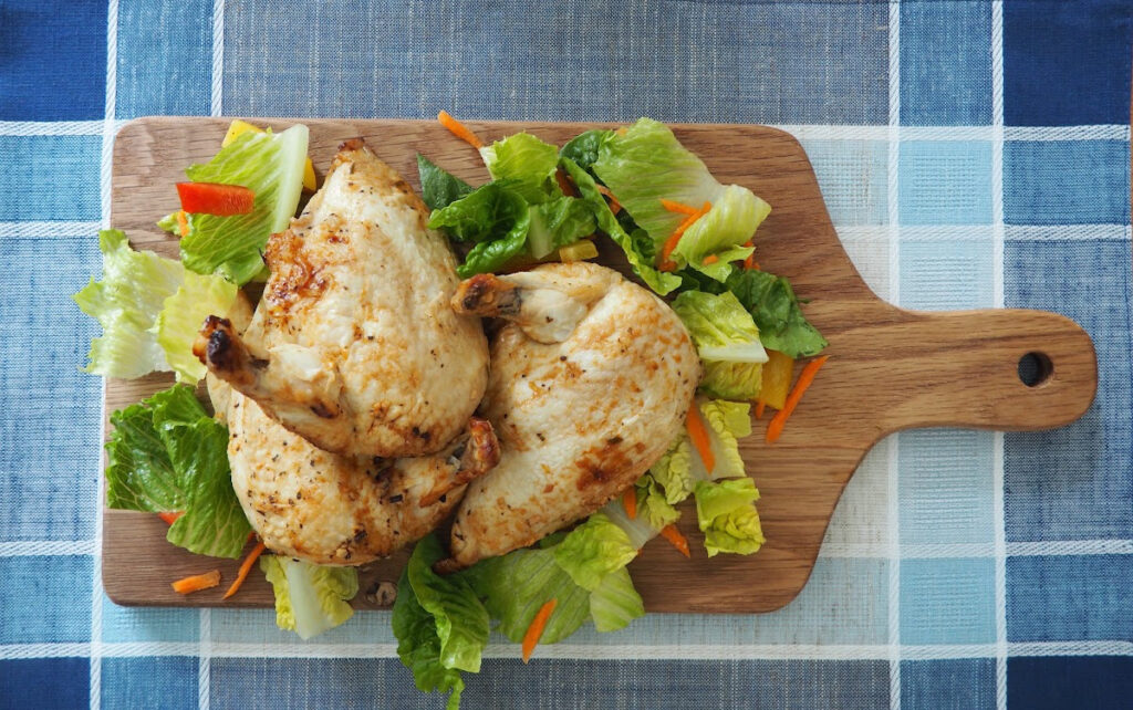 Cooked Chicken that was marinaded in the Easy Lemon and Herb Chicken Marinade served on a lettuce lined bread board