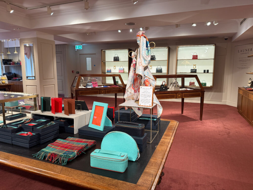First floor F&M - a table of scarves and accessories in the foreground, handbags in the background