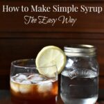 A glass of ice tea with a lemon garnish and a Mason jar full of simple syrup behind it