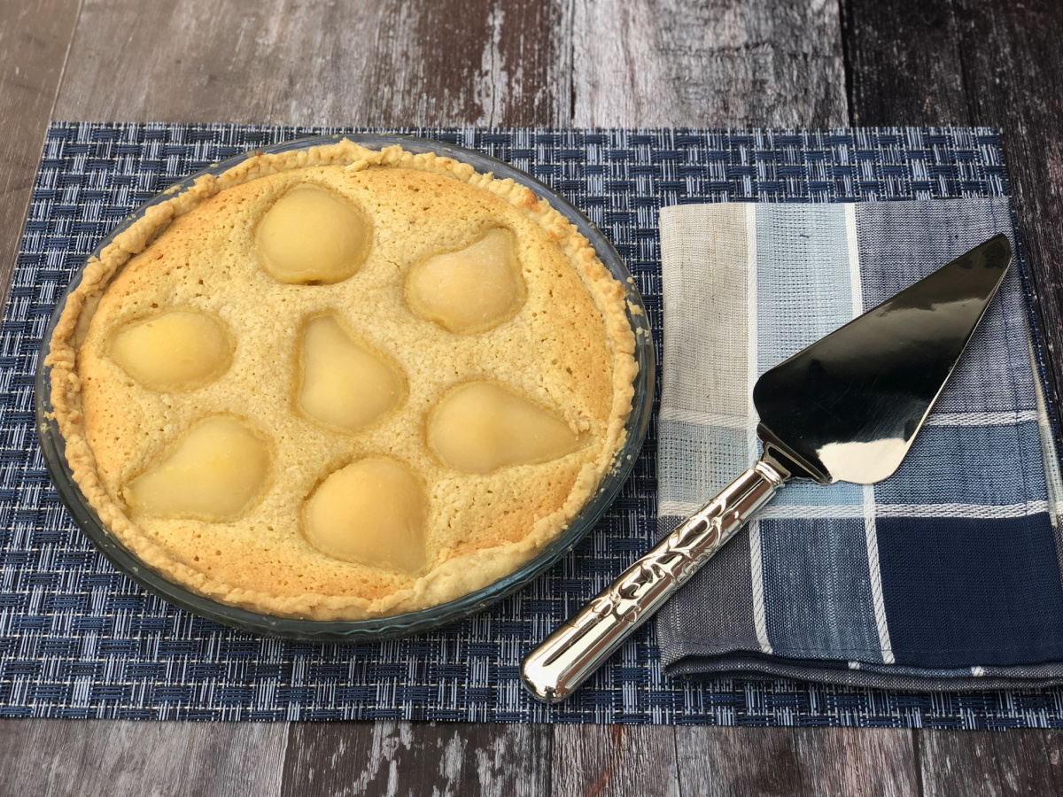 A whole Pear Tart sitting on a blue placemat