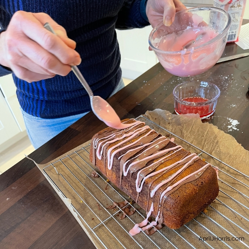 Drizzling pink glaze over a loaf cake