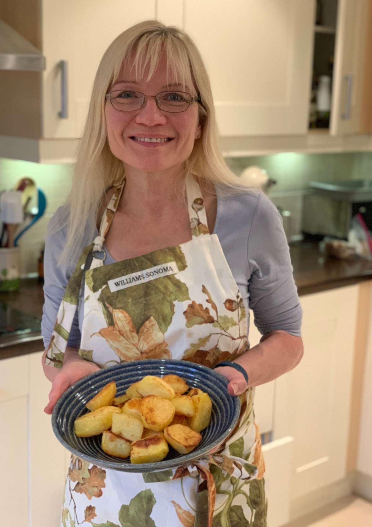 April Harris holding a bowl full of golden brown roast potatoes
