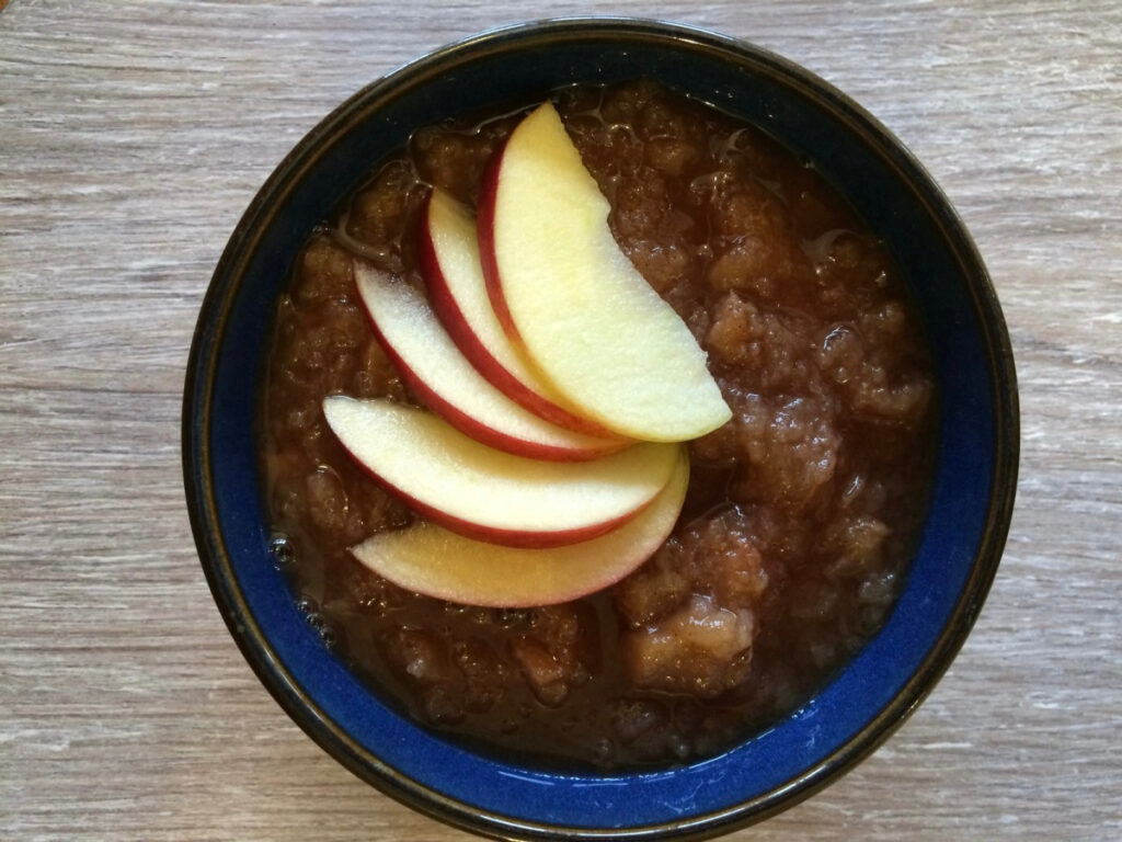Crock Pot Apple and Pear Sauce served in a bowl with sliced apples fanned on top for decoration