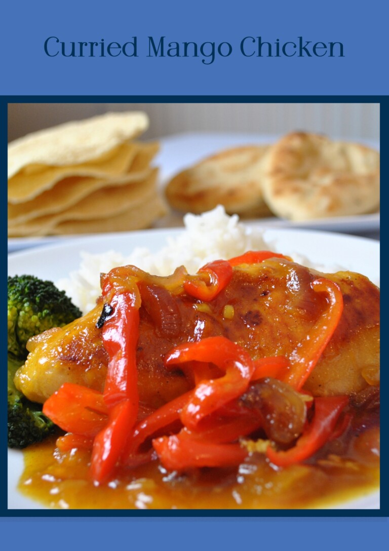Curried Mango Chicken served on a plate with papadam and nan breads in the background