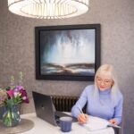 April J Harris image for how to make resolutions that work - April is sitting at a table writing in a notebook