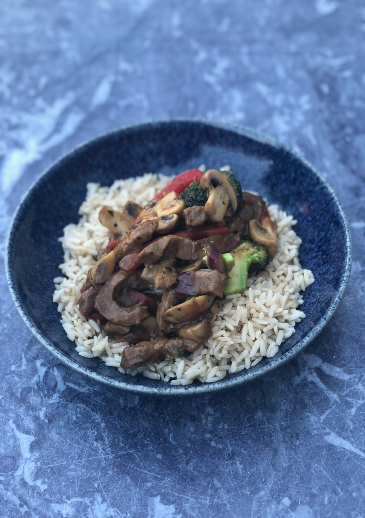 Beef and Vegetable Stir Fry served over rice in a blue bowl