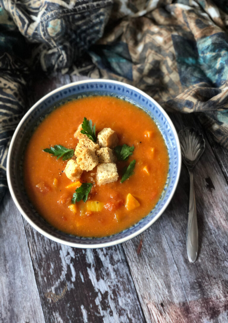 A bowl of vegetarian Mulligatawny Soup garnished with croutons and parsley