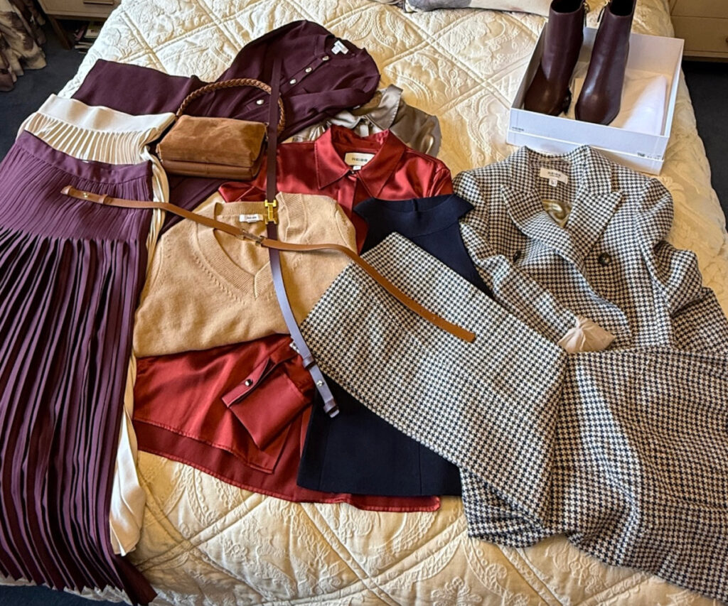 2025 wardrobe refresh outfit flat lay idea including ncluding a burgundy pleated skirt, red blouse, check houndstooth suit, boots, belts and more