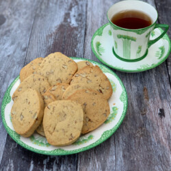 Orange Pecan Cookies served on a china plate with a green design, cup of tea in the background