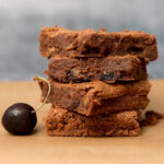A stack of red wine brownies with a cherry alongside