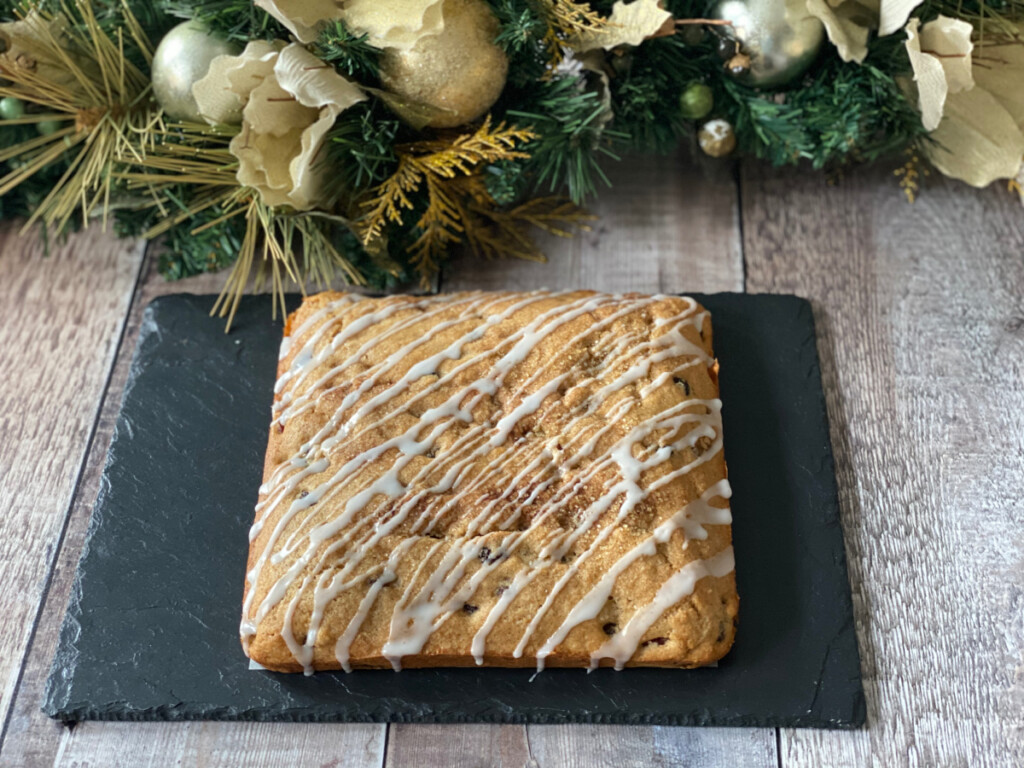 a whole Mincemeat Cake served on a slate with Christmas foliage in the background