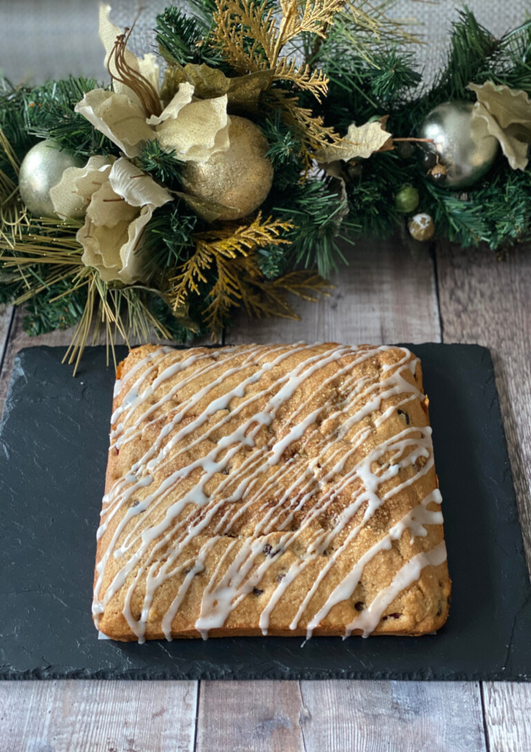 a whole Brandy and Mincemeat Cake served on a slate with Christmas foliage in the background