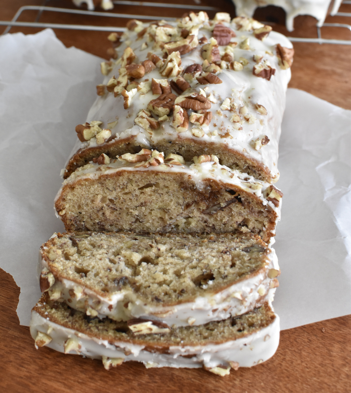 A glazed spiced banana nut loaf sitting on some greaseproof paper. 