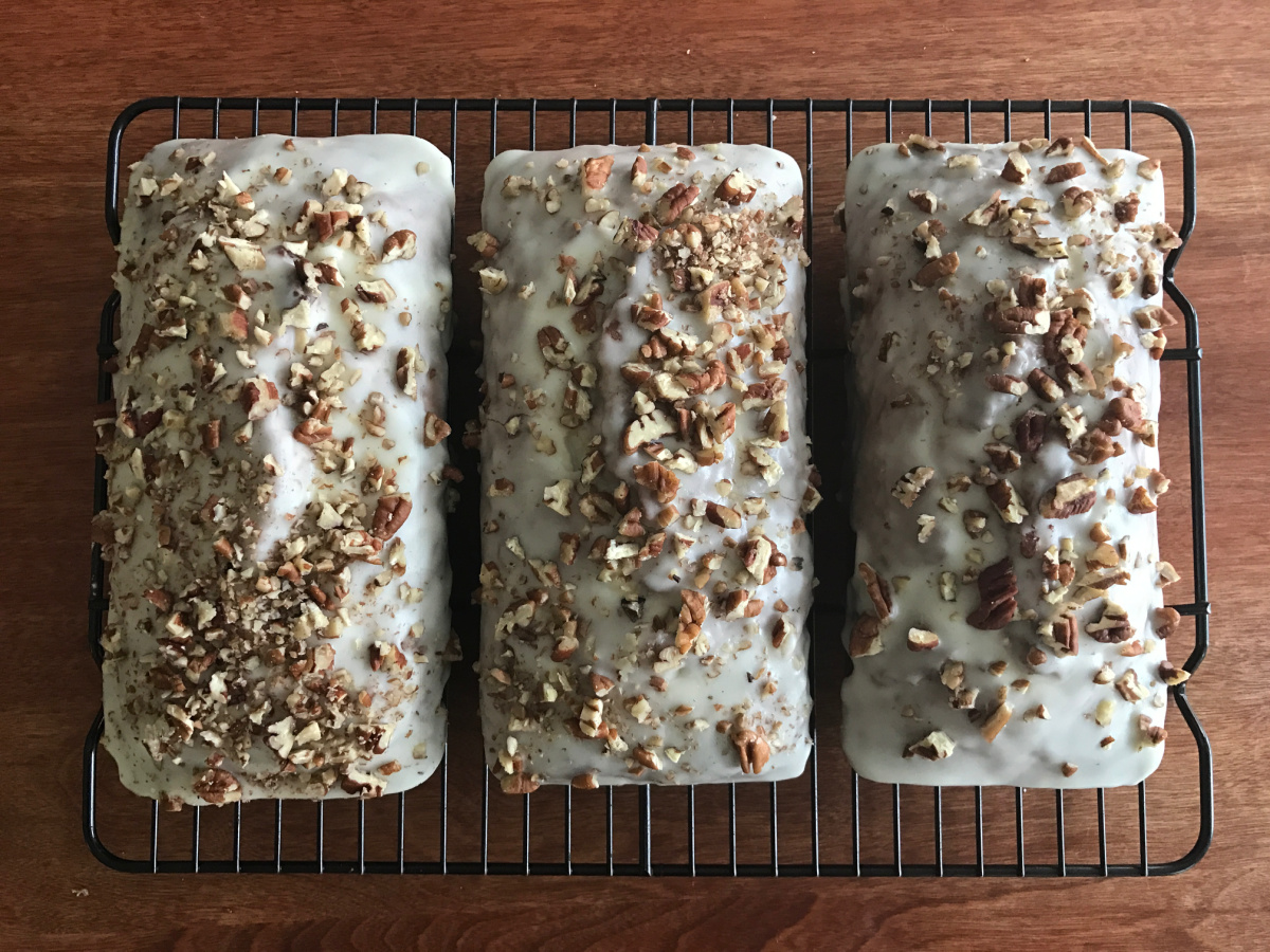 Flat lay shot of 3 glazed and decorated Spiced Banana Nut Loaf on a wire rack