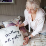 January 2023 Edition Hearth and Soul Link Party - a woman arranging a pillow on a freshly made bed