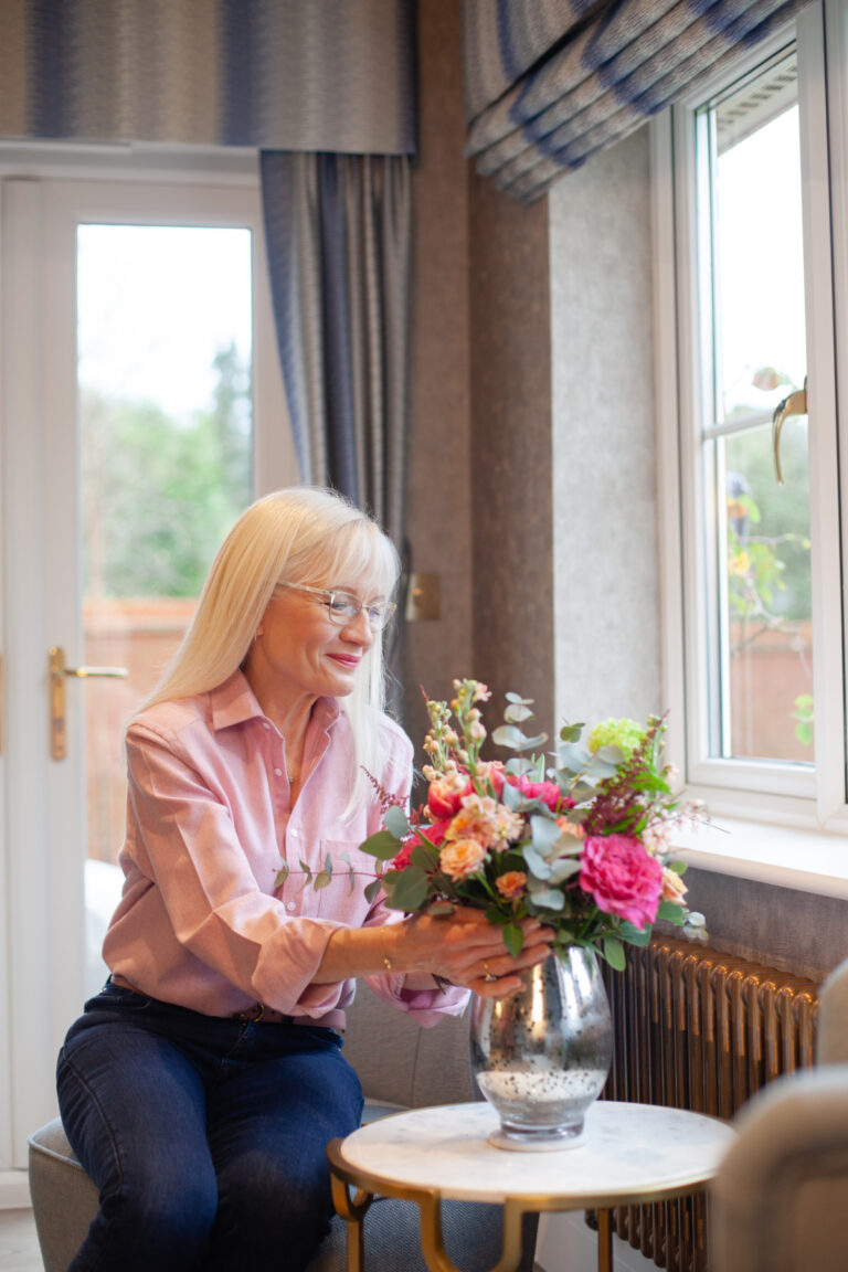 April Harris arranging spring flowers by a window in her kitchen