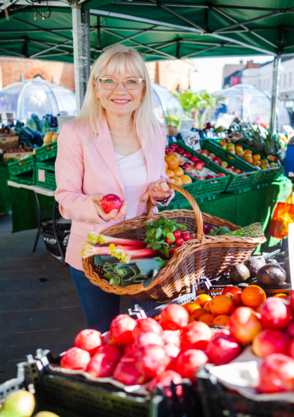 April J Harris in a farmer's market choosing fruit and vegetables to share easy ways to eat less meat