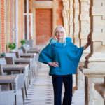 Adding colour to your wardrobe - April J Harris wearing a turquoise poncho and standing by a pillar