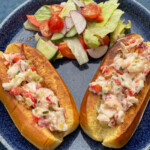 Two Lobster Rolls served on a plate with a side of salad