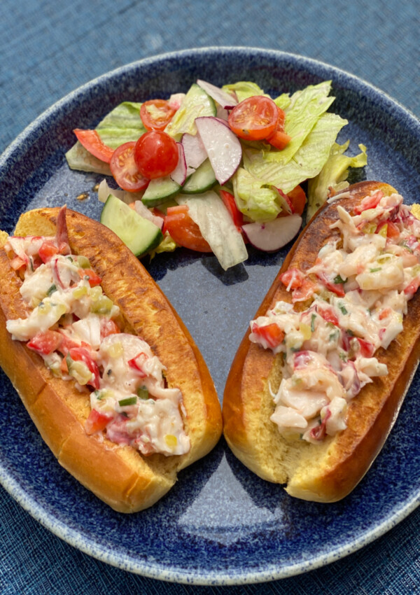 Two Lobster Rolls served on a plate with a side of salad
