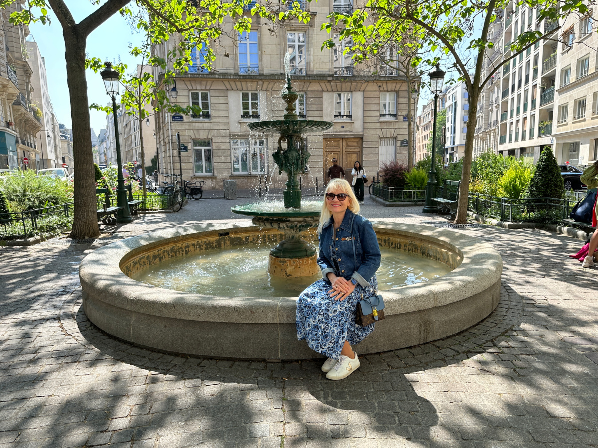 April Harris sitting on a fountain in a square in Paris