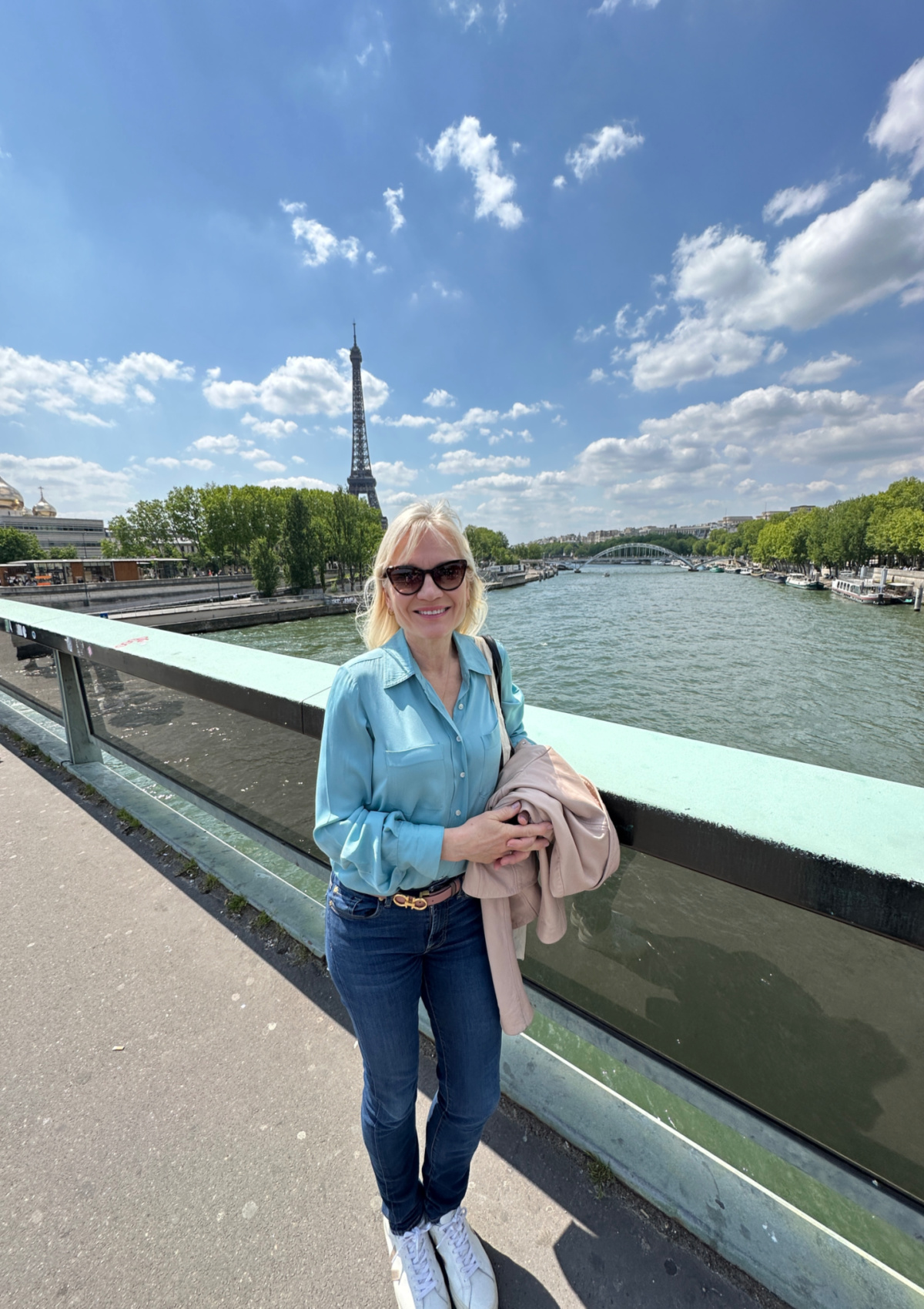April Harris standing on a bridge in Paris with the Eiffel Tower in the background. 