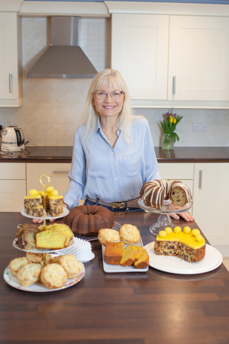 April Harris standing behind a kitchen island full of Easter Afternoon Tea treats